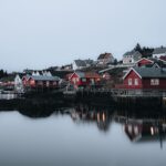 Czerwone drewniane domy odbijające się w spokojnej wodzie w Nordland o zmierzchu
