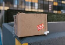 Delikatna kartonowa paczka z napisem fragile na betonowym murku w mieście