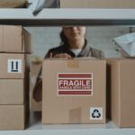 Pracownik układa delikatne kartony z napisem fragile w magazynie