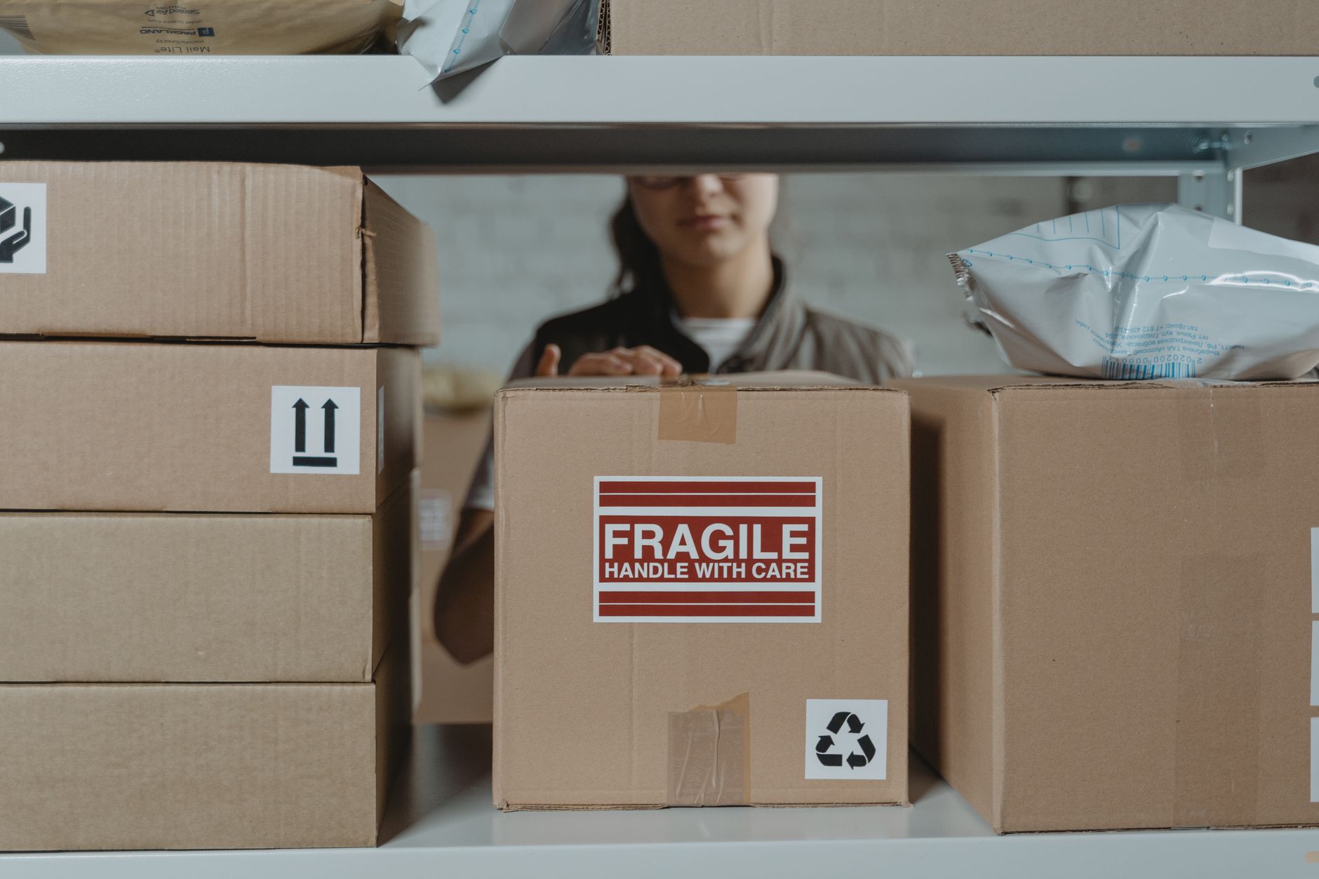 Pracownik układa delikatne kartony z napisem fragile w magazynie