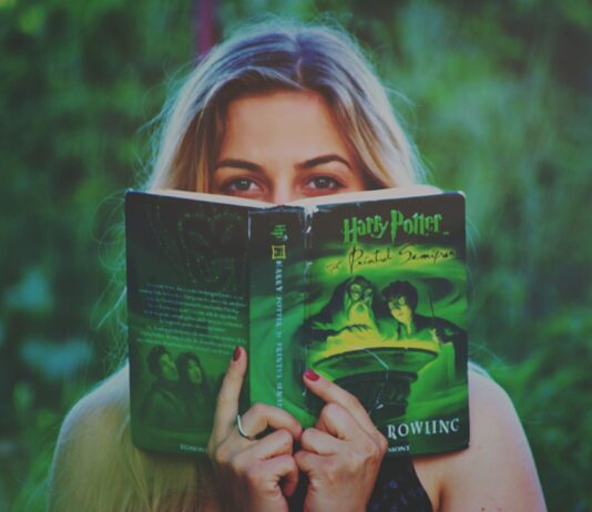 Kobieta czytająca książkę Harry Potter wśród zieleni