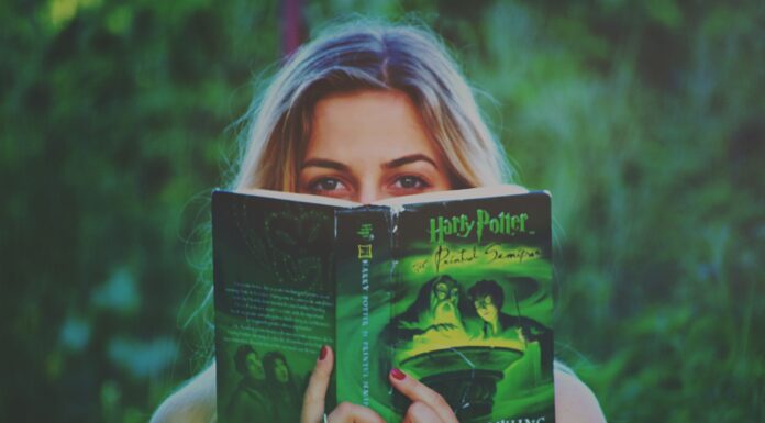 Kobieta czytająca książkę Harry Potter wśród zieleni