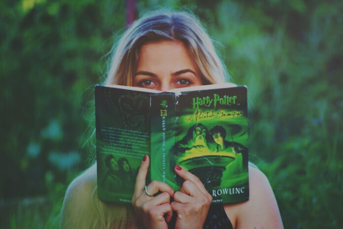 Kobieta czytająca książkę Harry Potter wśród zieleni Kobieta czytająca książkę Harry Potter wśród zieleni