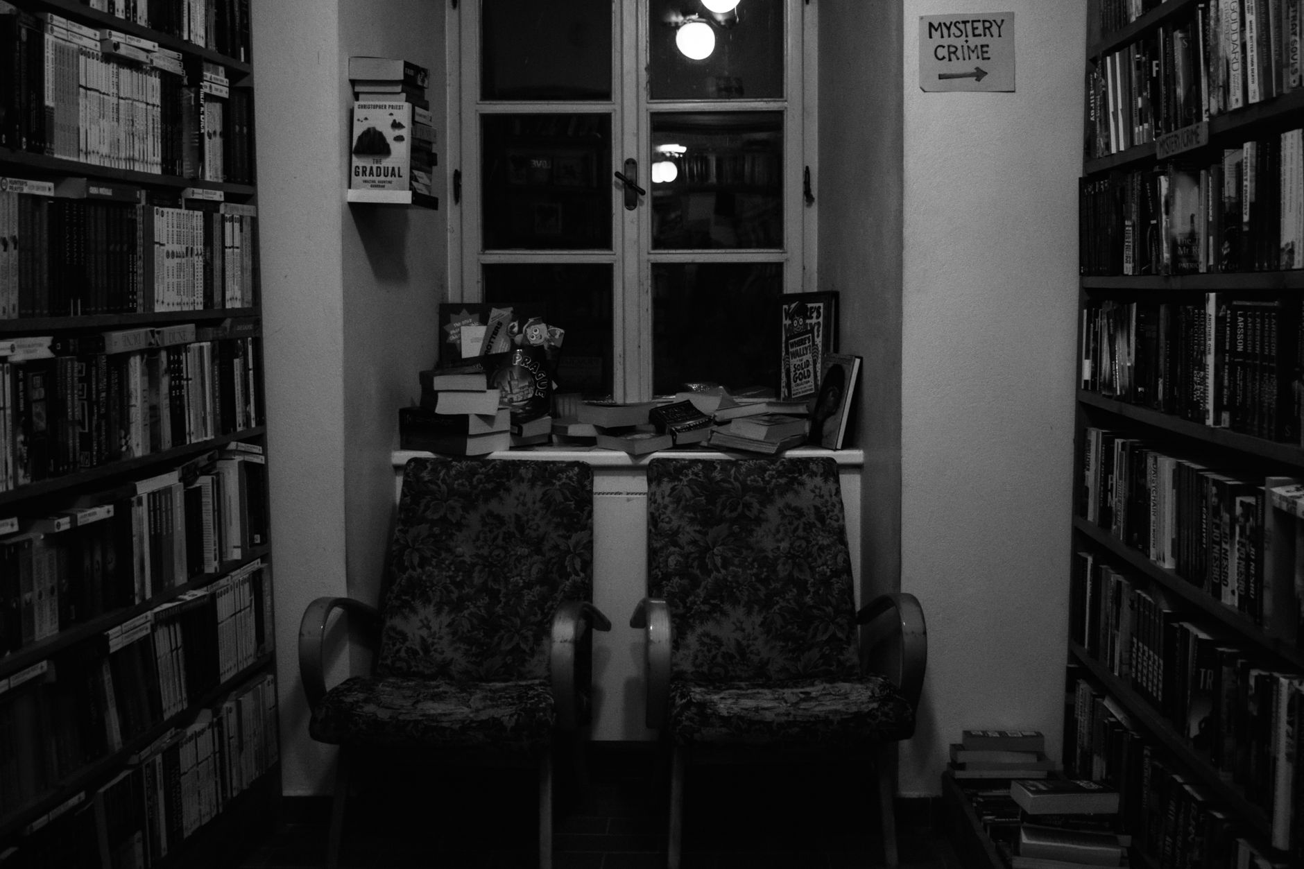 Przytulny kącik w bibliotece z fotelami obok półki z kryminałami