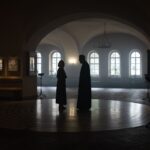 Sylwetki księdza i parafianki w spokojnym wnętrzu kościoła